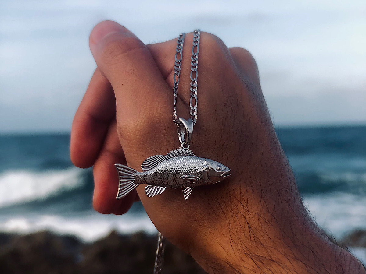 Silver mangrove snapper necklace in hand.